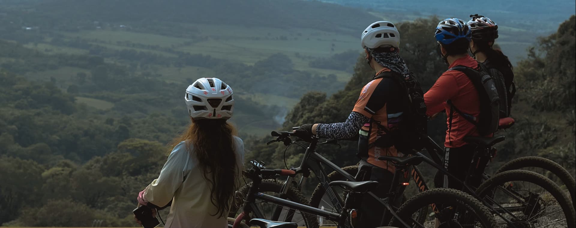 Ciclistas parados no topo de uma montanha contemplando a paisagem